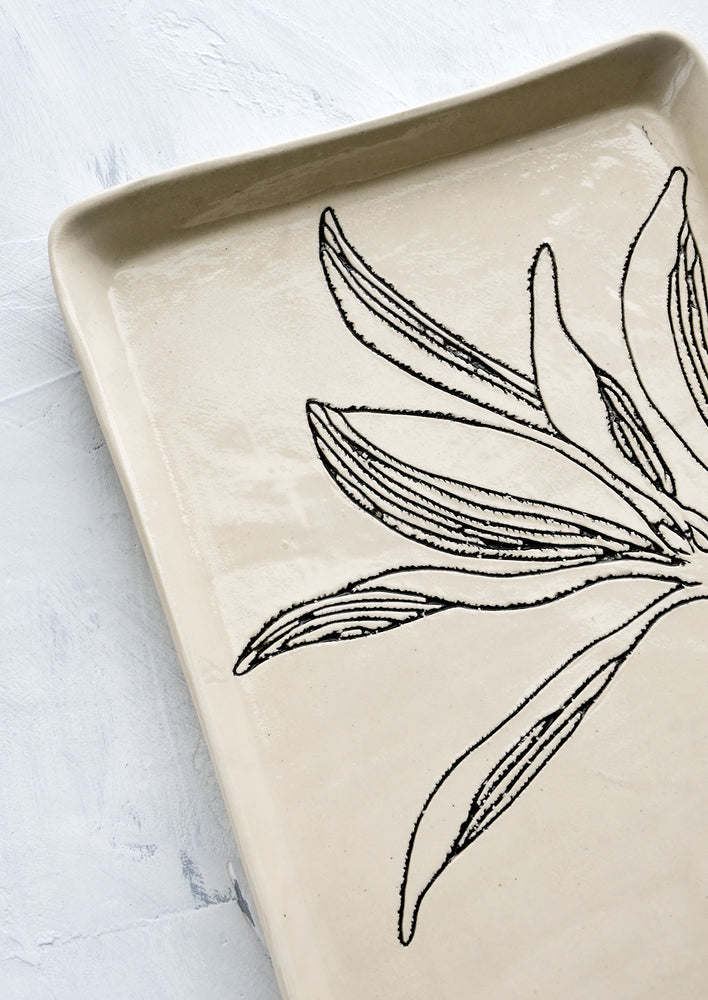 Black etched botanical detailing on a ceramic tray.