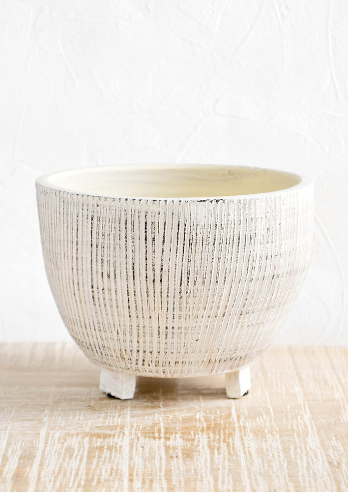 Round ceramic planter with tripod footed base. Allover ribbed texture with distressed black detail.