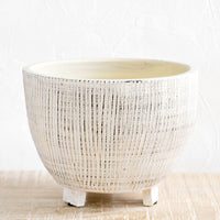 1: Round ceramic planter with tripod footed base. Allover ribbed texture with distressed black detail.