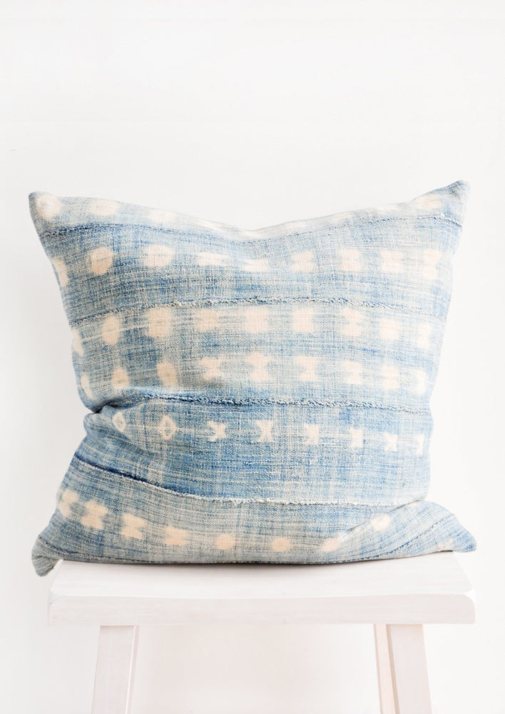 A square throw pillow in faded indigo shibori fabric.