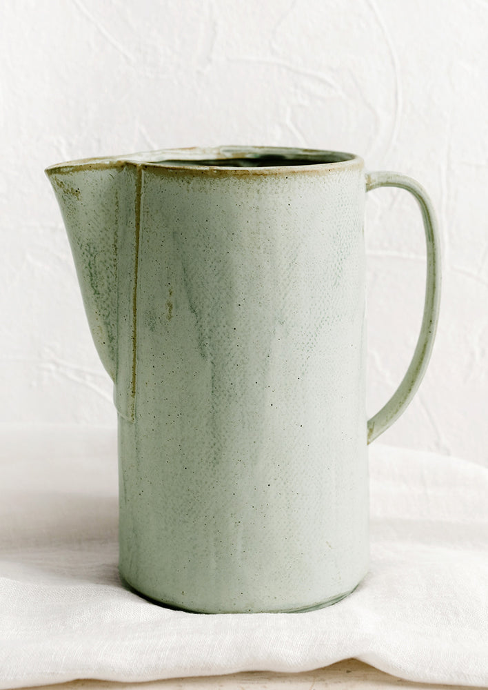 A ceramic pitcher with a minty rustic glaze