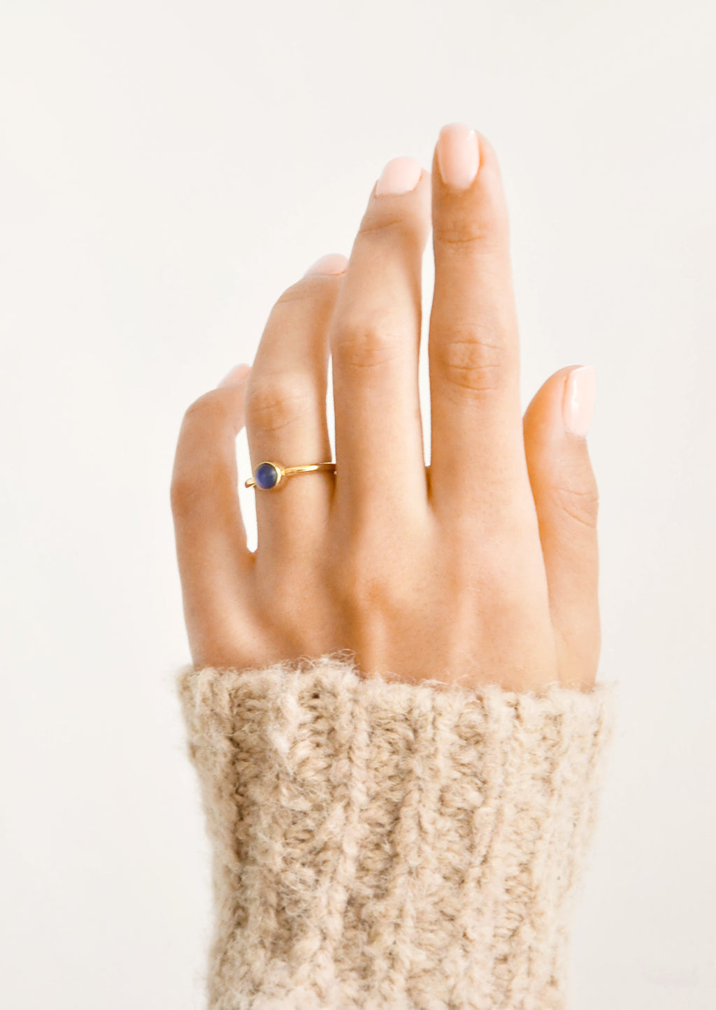2: A woman's hand with a blue stone ring on her ring finger.