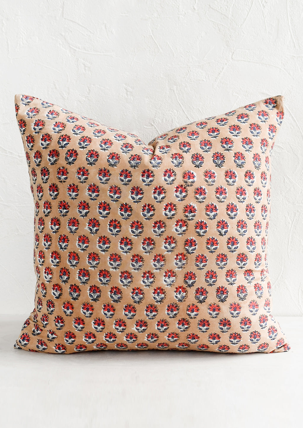 1: A block printed pillow in light brown with red and dusty blue flower print.