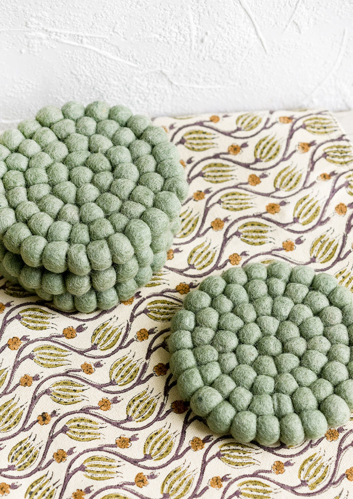 A set of round felted wool coasters in mint green.