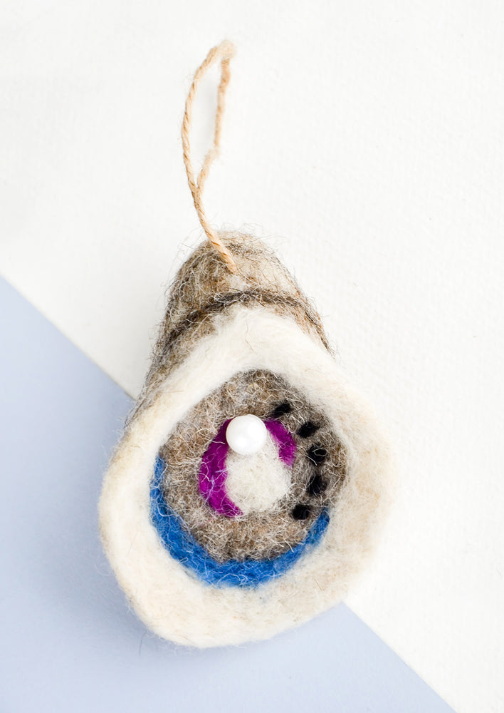 1: A holiday ornament in felted wool designed to look like an oyster with pearl.