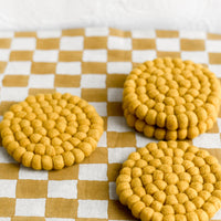 Mustard: A set of round felted wool coasters in mustard.
