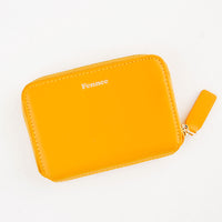 Mandarin: Small orange leather zip wallet with Fennec embossed in small gold letters at top of wallet face.