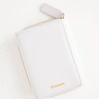 Cloudy: Light grey leather wallet that zips on three sides, in a closed position, with matching tab pull.