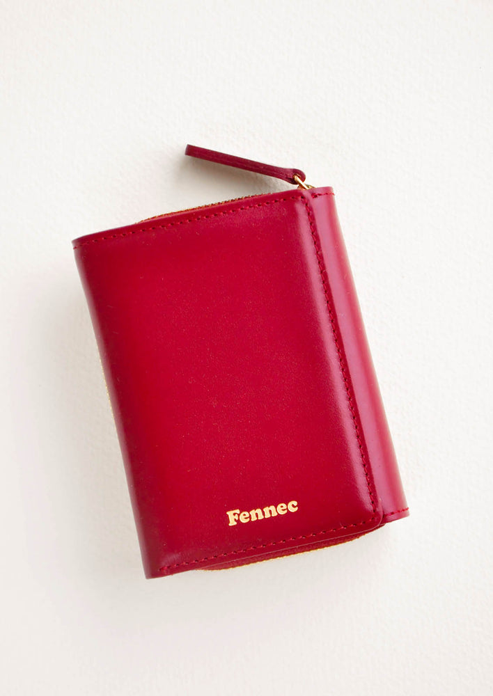 Marsala: Dark red leather wallet that zips on three sides, in a closed position, with matching tab pull.