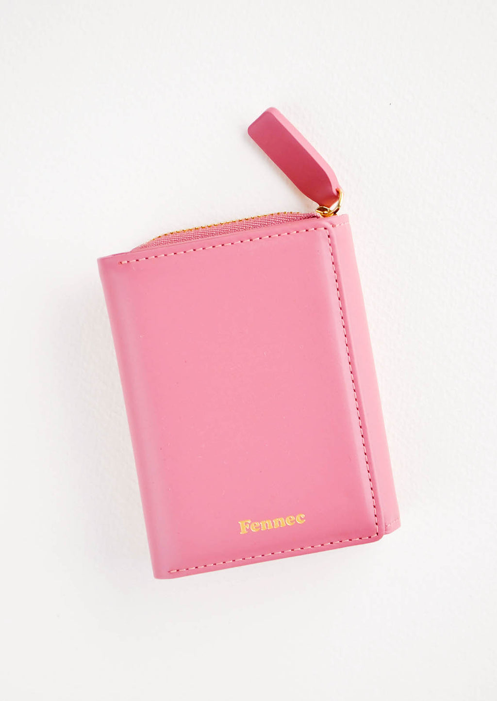 Rose: Rose red leather wallet that zips on three sides, in a closed position, with matching tab pull.