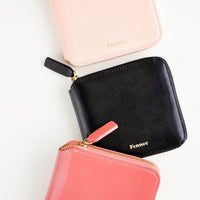 1: Three leather zip wallets in pale pink, black, and deep pink.