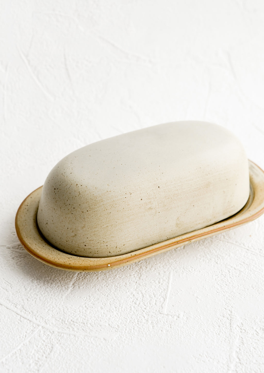 2: An oblong ceramic butter dish and tray in a softly speckled tan glaze.