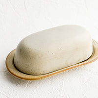2: An oblong ceramic butter dish and tray in a softly speckled tan glaze.