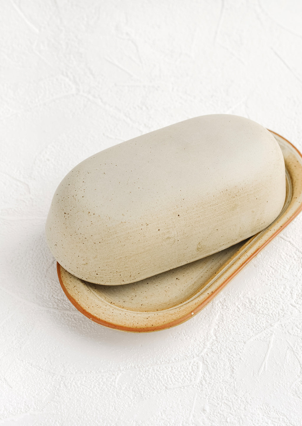 4: An oblong ceramic butter dish and tray in a softly speckled tan glaze.
