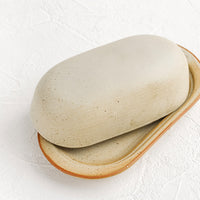 4: An oblong ceramic butter dish and tray in a softly speckled tan glaze.