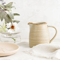 2: A tan ceramic pitcher with striped texture.