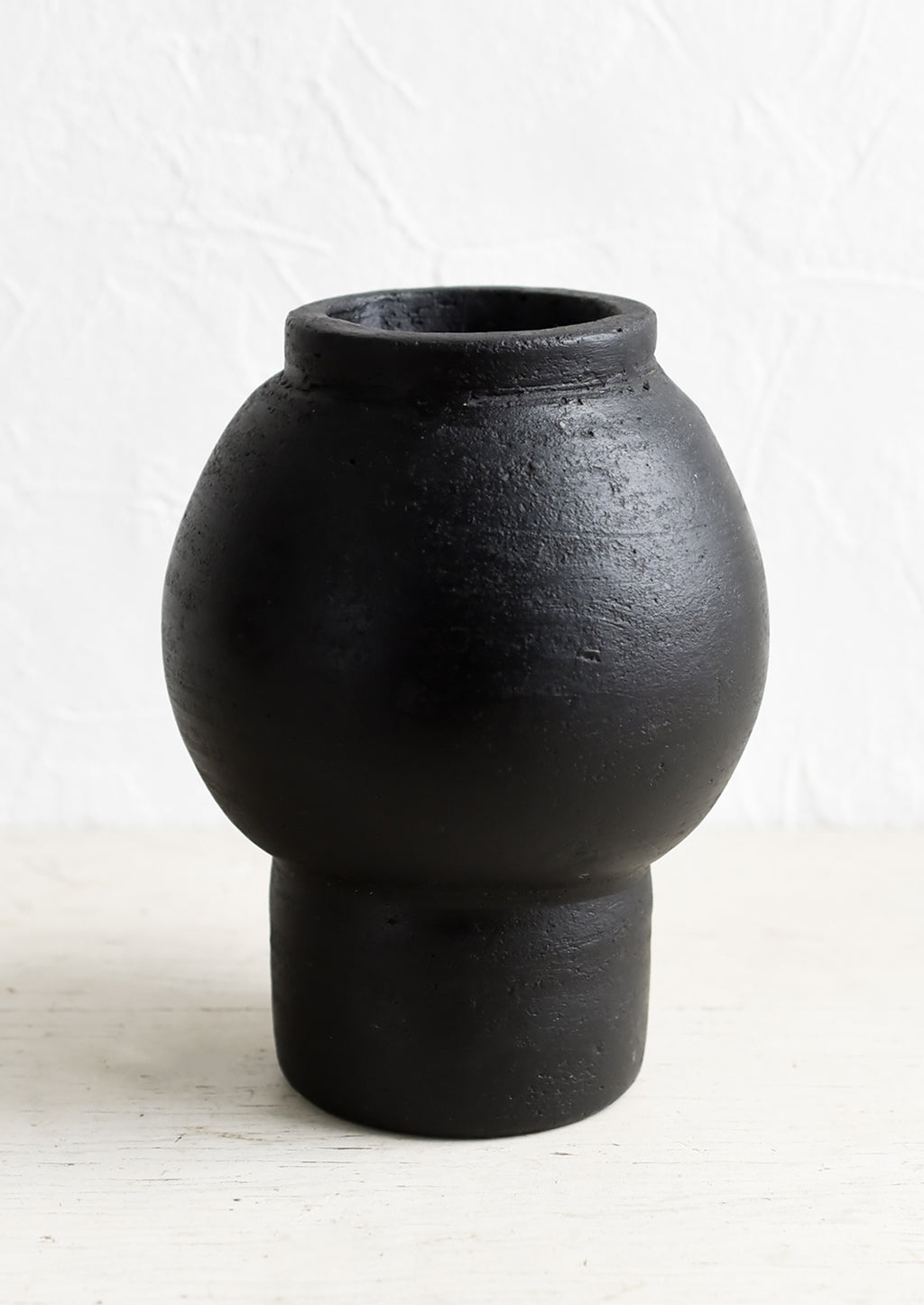 2: A vase in black terracotta clay with round shaped center and footed base.