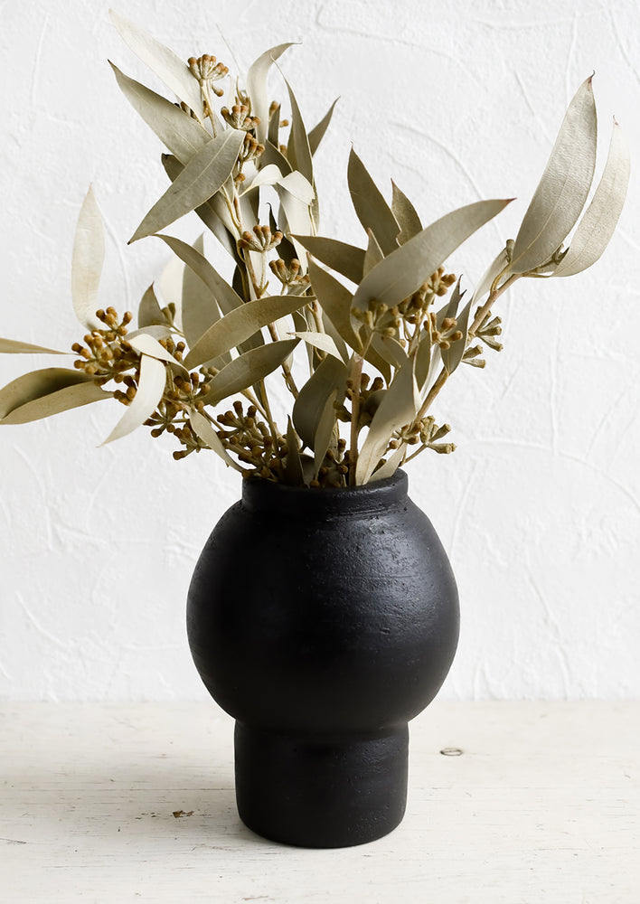 1: A shapely black vase with dried eucalyptus stems.