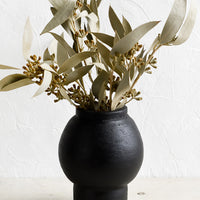 1: A shapely black vase with dried eucalyptus stems.