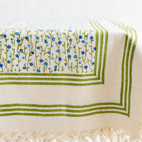 1: A floral block printed tablecloth with tassel trim, on a table.