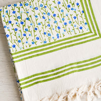 2: A folded cotton tablecloth with green border and green and blue floral pattern.