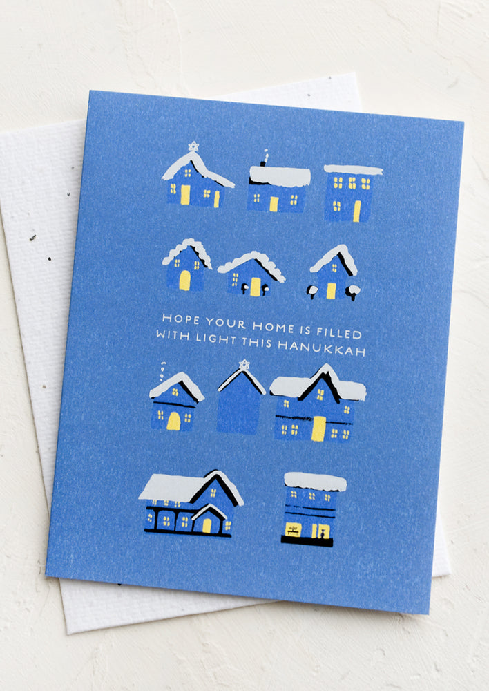 A greeting card with illustration of lit up houses, text reads "Hope your home is filled with light this Hanukkah".