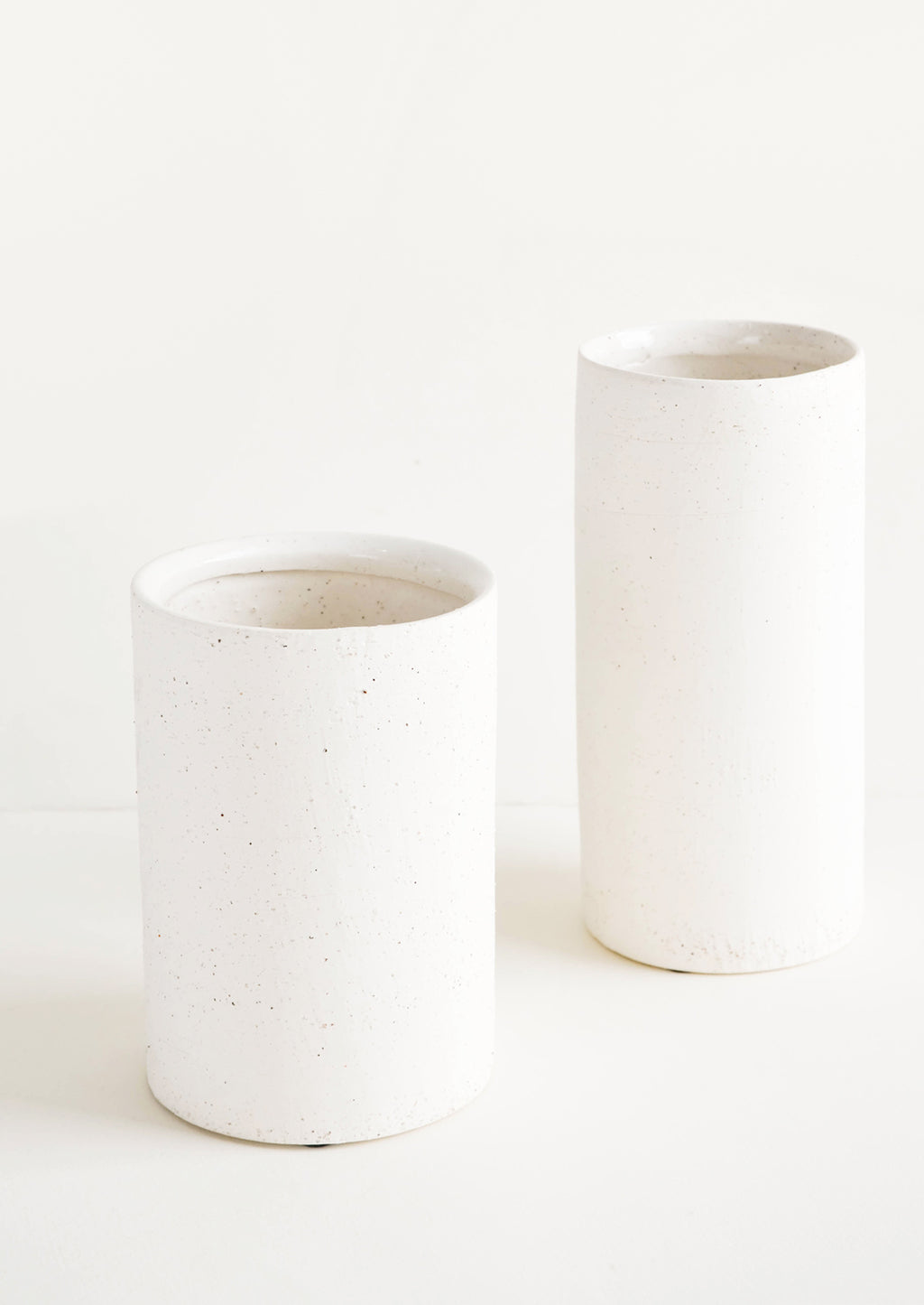 4: Vases made from white, textured concrete-like material in two different sizes, short and tall