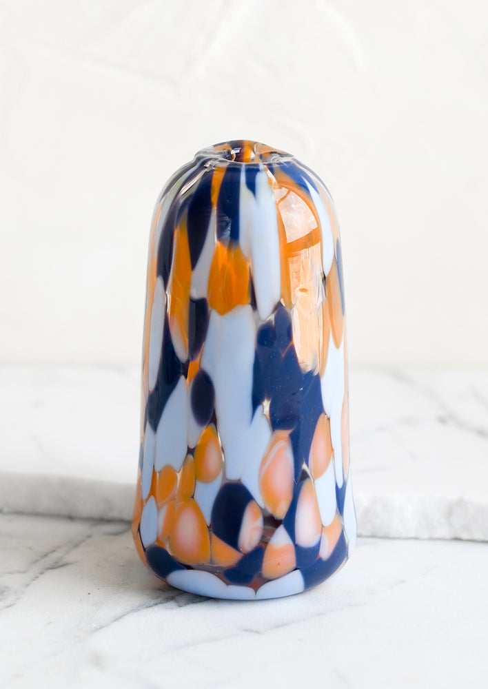 A tapered bud vase in hand blown glass with blue and orange speckle pattern.