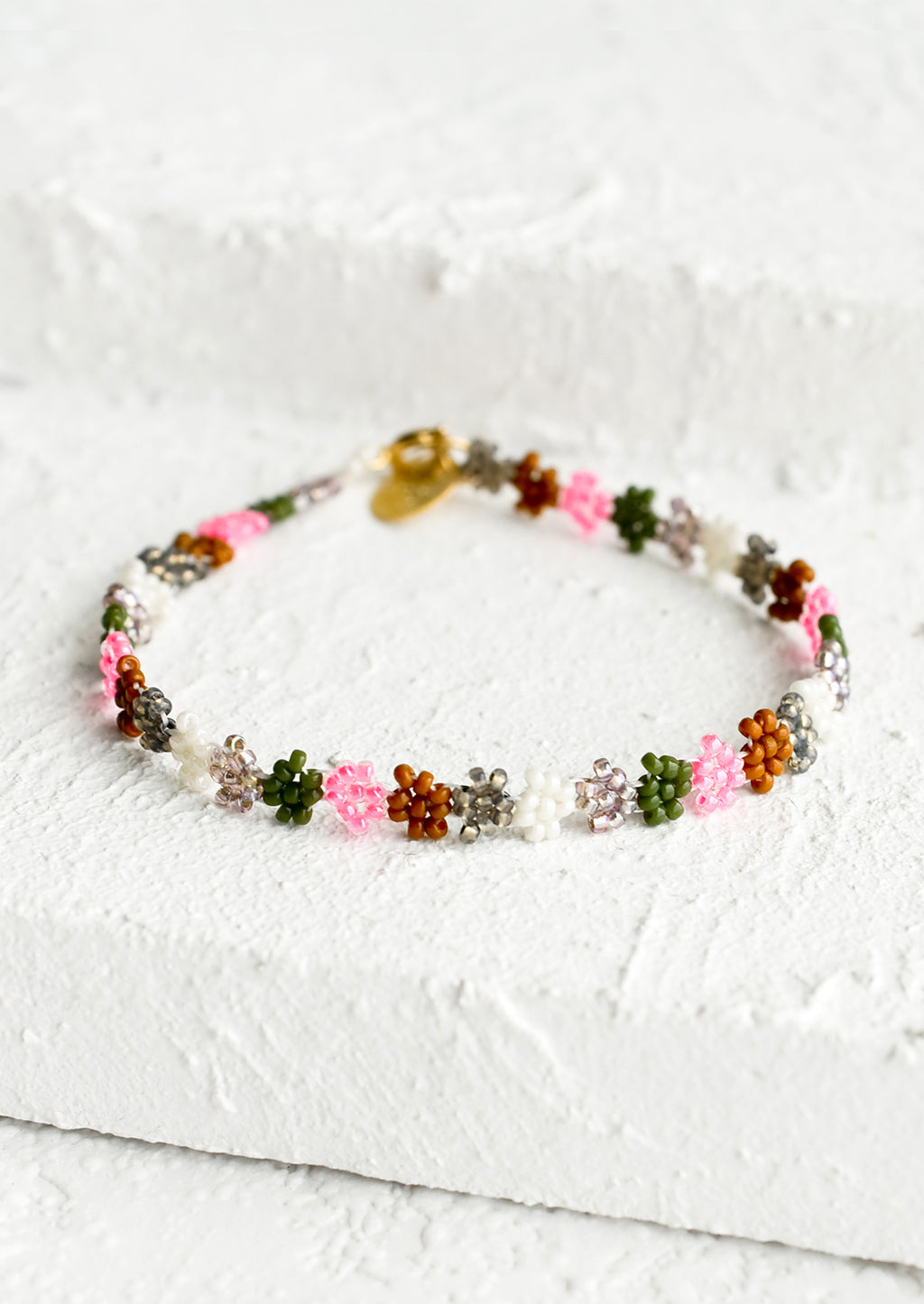 Neon Pink Multi: A beaded bracelet in flower shape in neon pink, olive, white and brown.