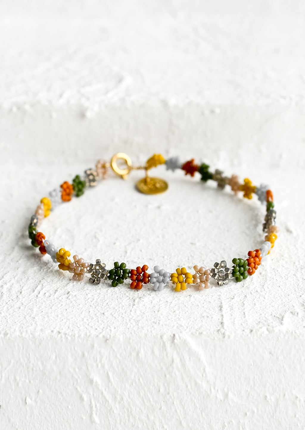 Spice Multi: A beaded bracelet in flower shape in rust, grey, mustard and olive.