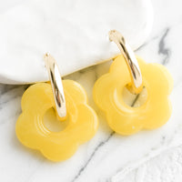 Lemon: A pair of earrings with gold huggie hoop base and yellow flower charm.