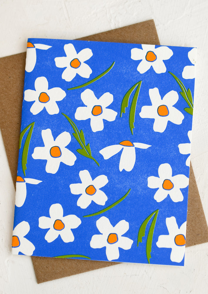 A letterpressed card with bright blue background and white and orange flowers.