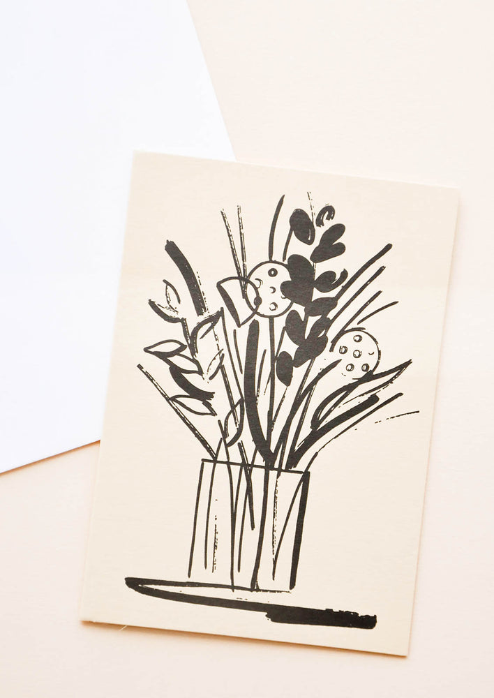 A white envelope and tan greeting card featuring an illustrated floral arrangement in black.