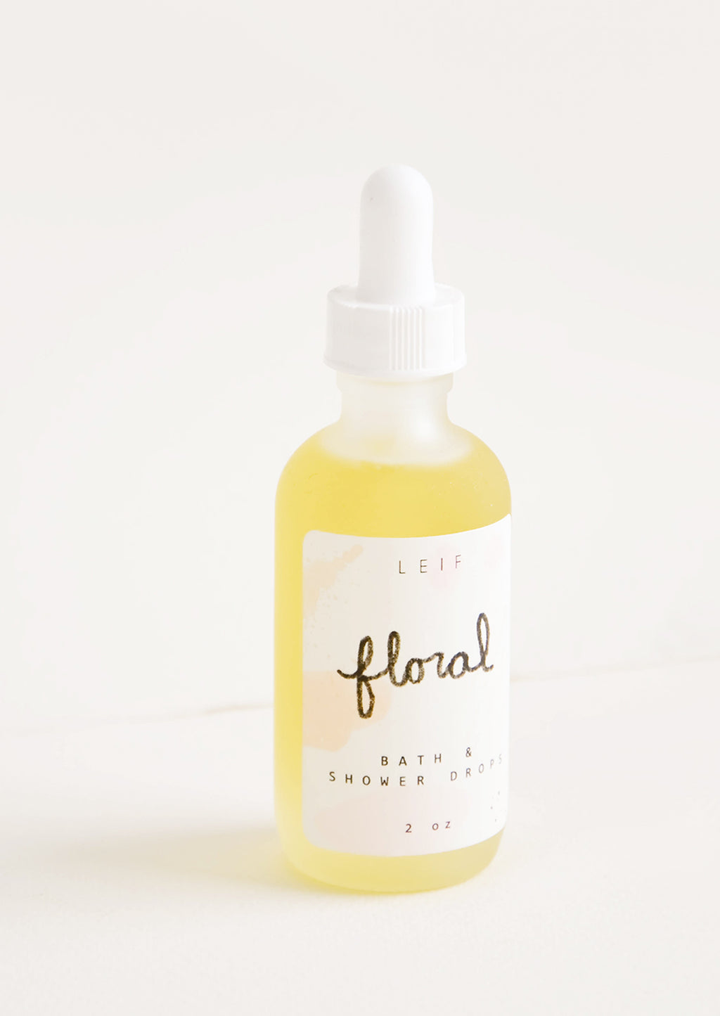 Floral: A small frosted glass dropper bottle with a white lid and label reading "floral" filled with a pale yellow liquid.