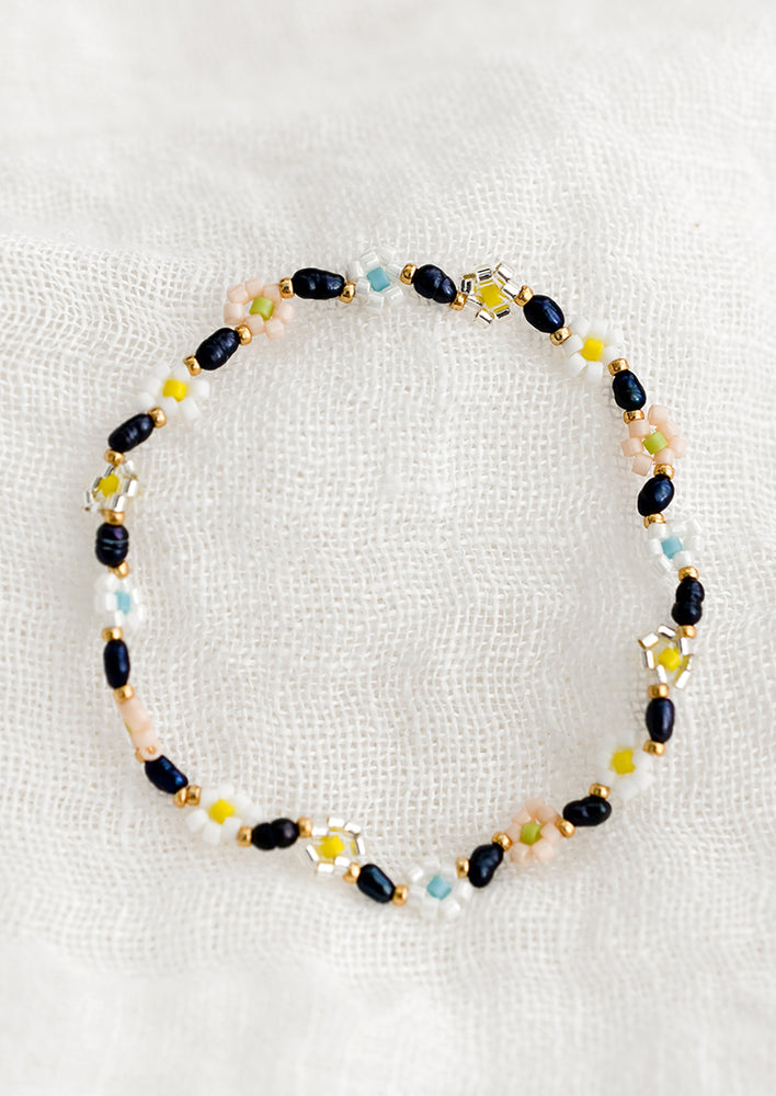 A beaded bracelet with black pearls and multicolor flowers.