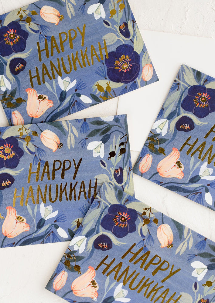 Greeting cards with blue floral print reading "happy hanukkah".