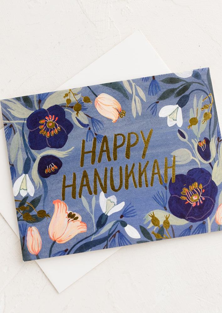A greeting card with blue floral print reading "happy hanukkah".