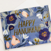 Single Card: A greeting card with blue floral print reading "happy hanukkah".