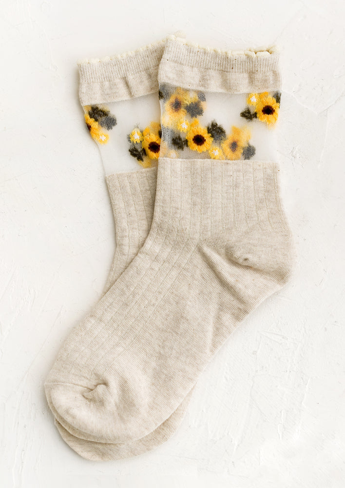 1: A pair of oatmeal colored socks with sheer mesh sunflower print band at ankle.