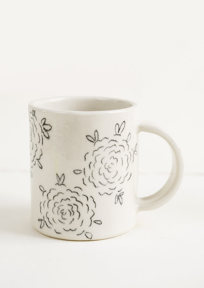 A handmade ceramic mug with white background and hand-painted floral line drawing print in black.