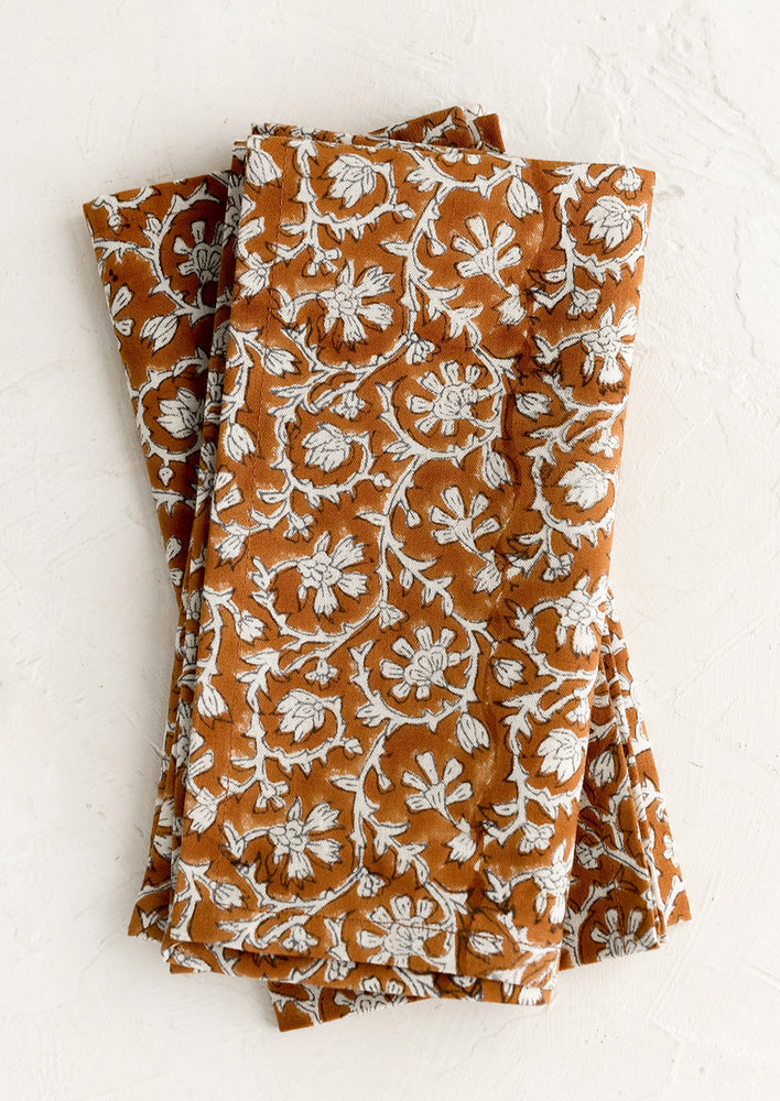A pair of amber and white colored napkins with floral print.