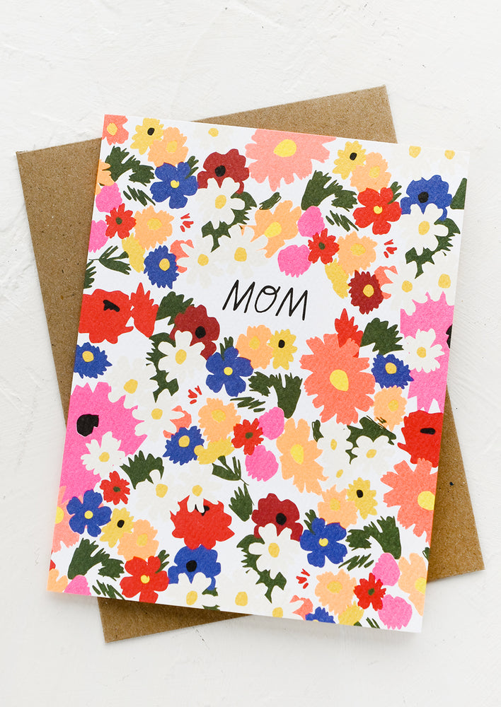 A greeting card with vibrant floral print reading "MOM".