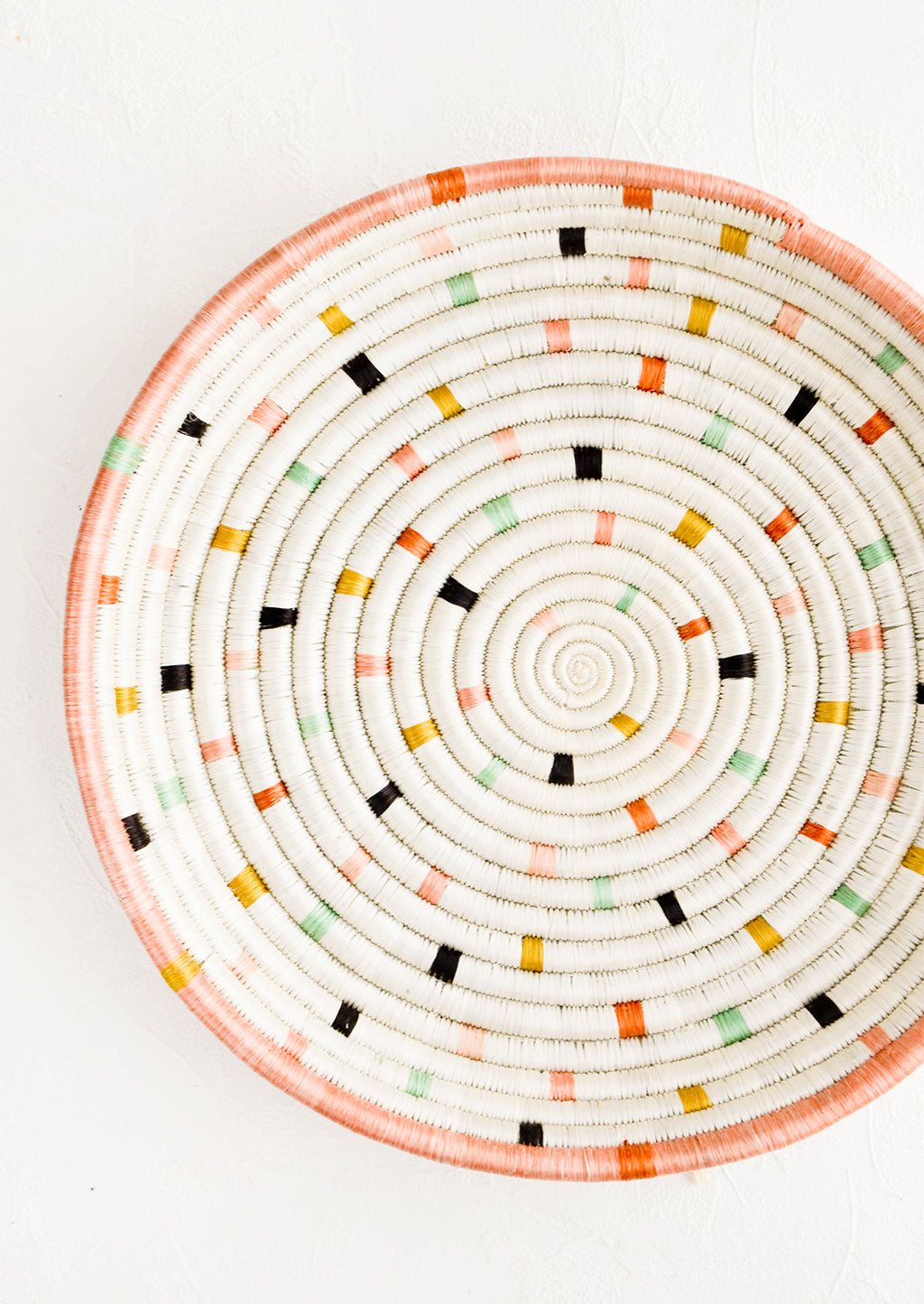 1: Round, shallow serving tray made from woven sweetgrass. Ivory with pastel colored dashes and peach rim.