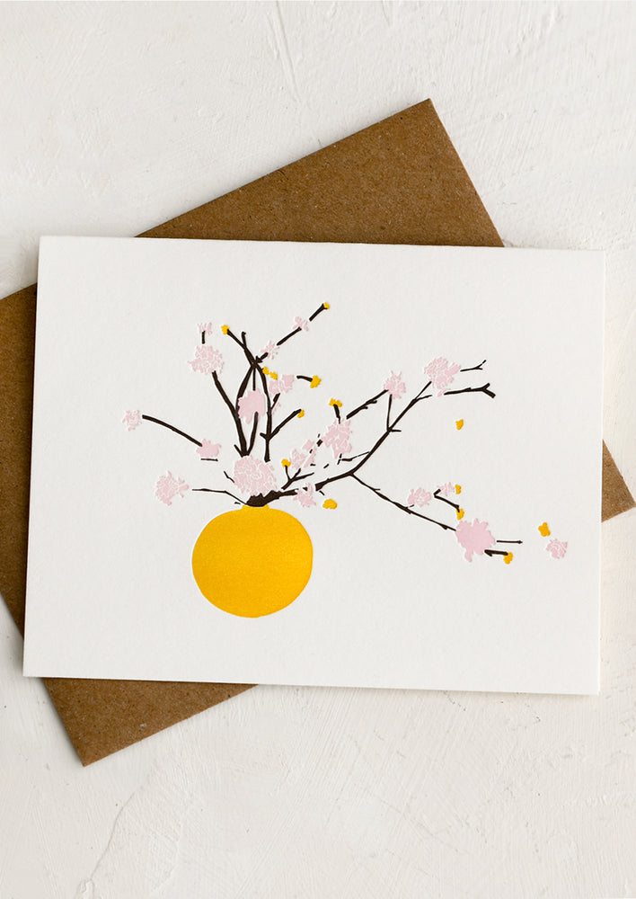 A card with letterpress image of pink flowering branches in a yellow vase.