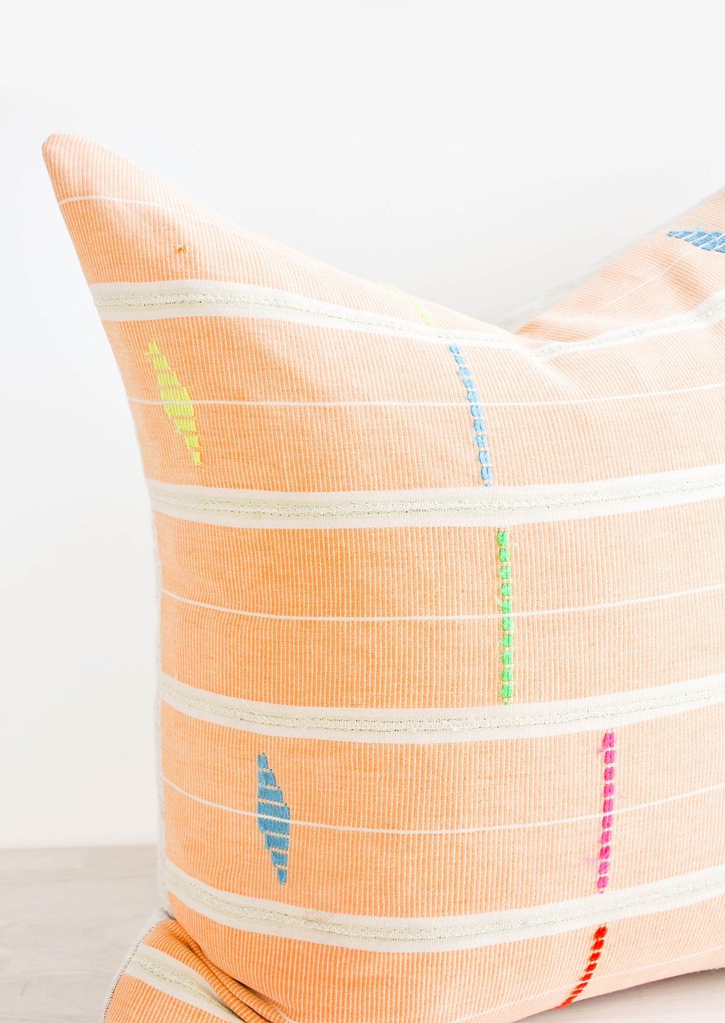 2: Close up of Square throw pillow made from vintage African fabric in bright orange with neon embroidery details.