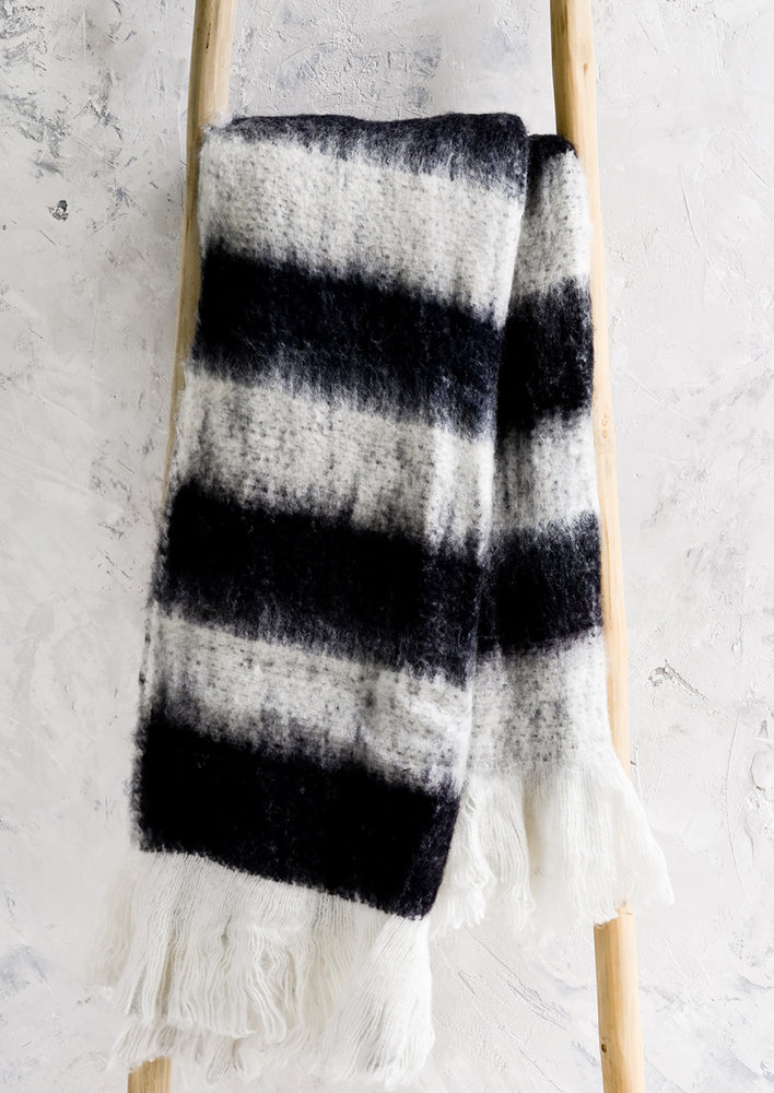 A fuzzy throw blanket in black and white stripes.