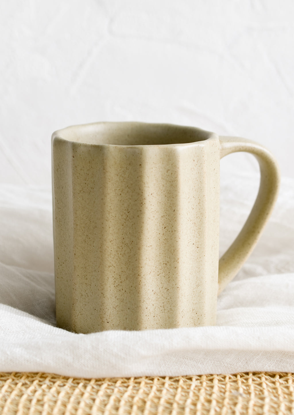 Sand: A fluted ceramic mug in sand.