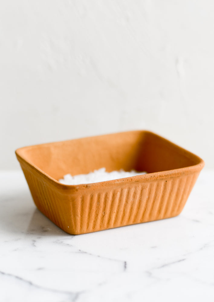 A rectangular dish with fluted texture in terracotta.