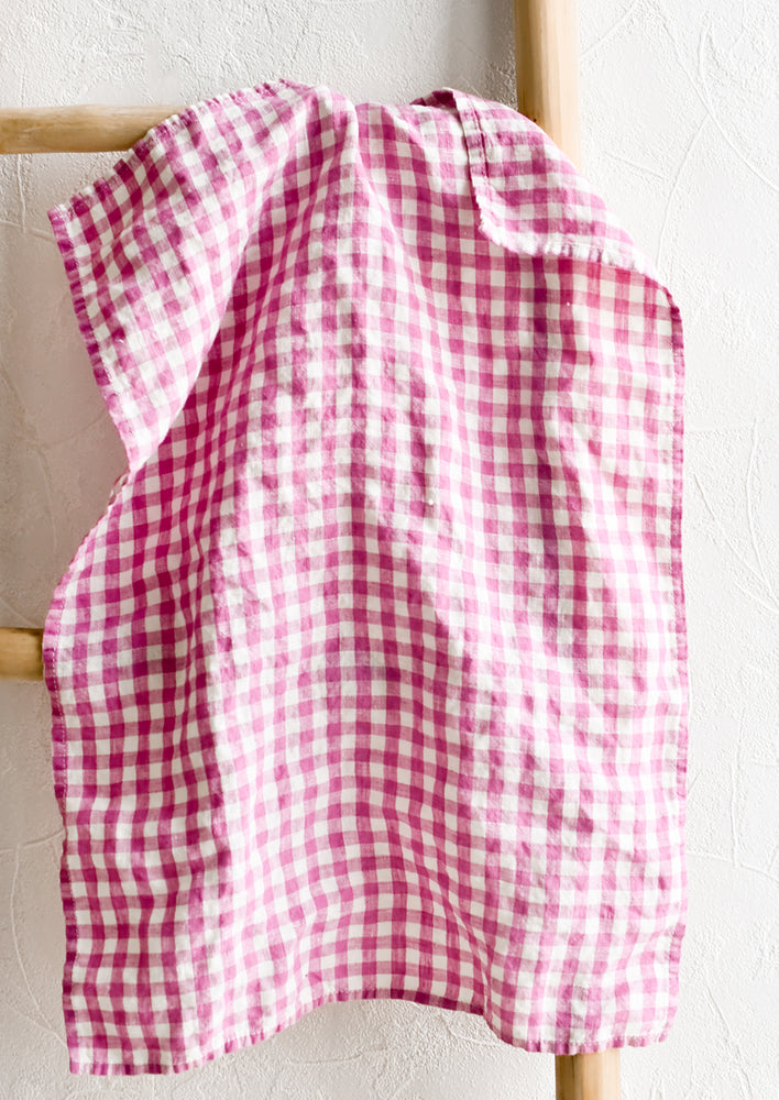 A linen tea towel in pink and white gingham.