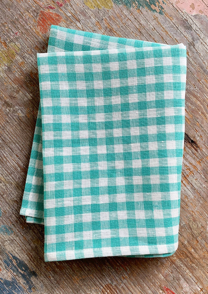 A linen tea towel in turquoise and white gingham.
